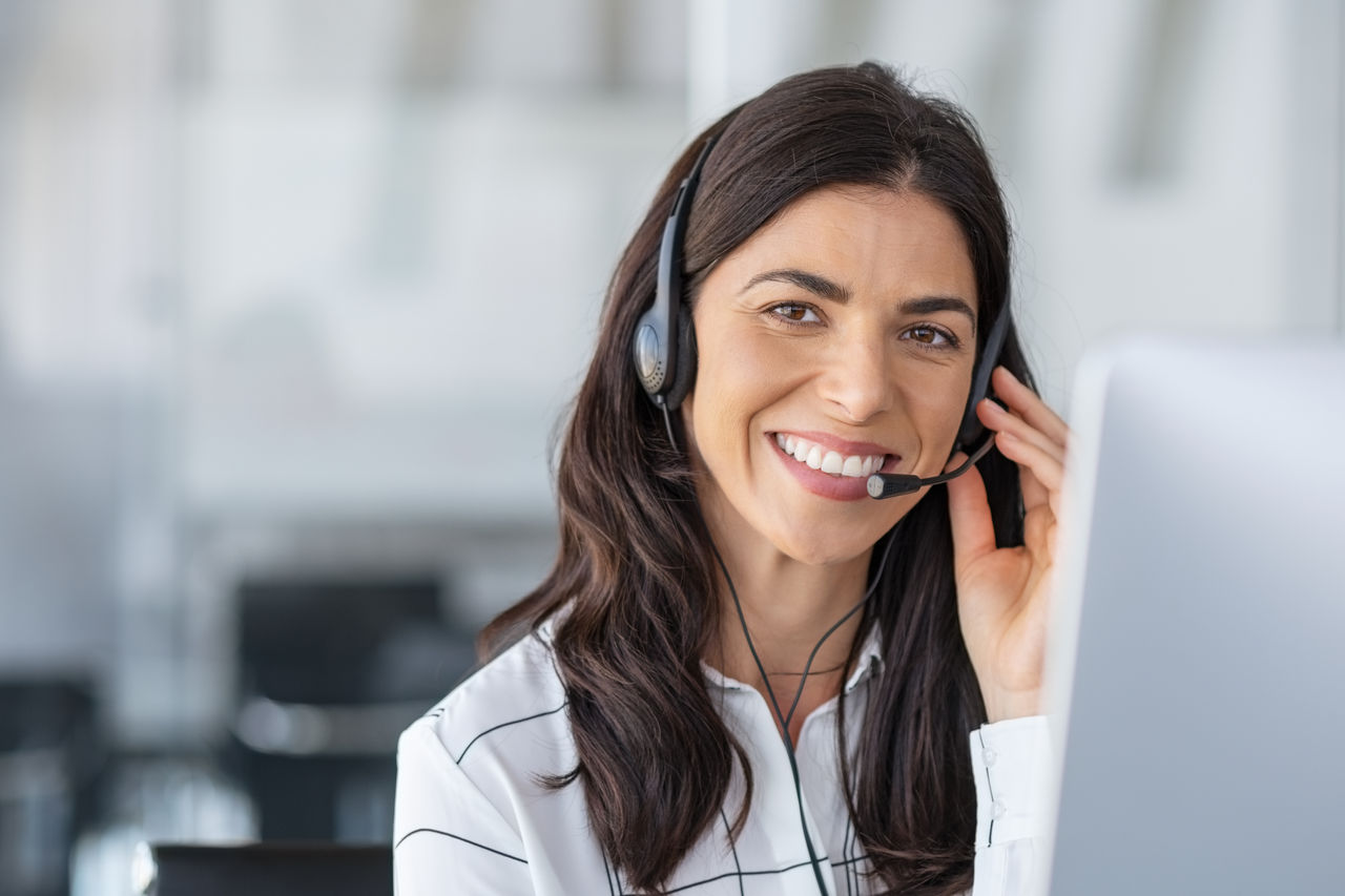 Call center agent with headset working on support hotline in modern office with copy space. Portrait of mature positive agent in conversation with customer over headset looking at camera.; Shutterstock ID 1607982631; purchase_order: Aluminum finishing; job: new website migration; client: CG; other: 