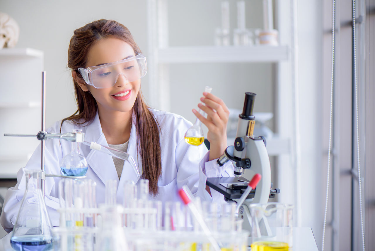 Female scientist working with laboratory collectors, holding a flask and test tubes
