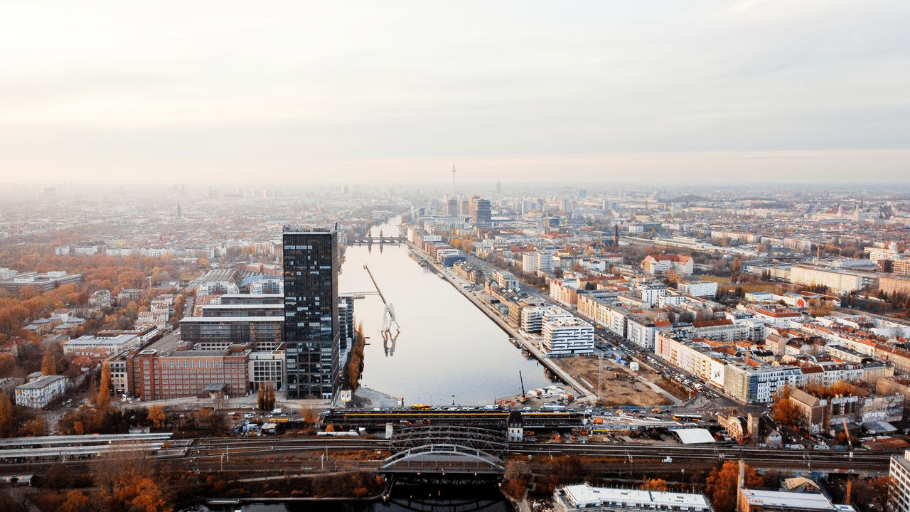 Aerial drone view of Berlin, Germany. District with river, yellowed trees, buildings and Berlin Television Tower in the distance