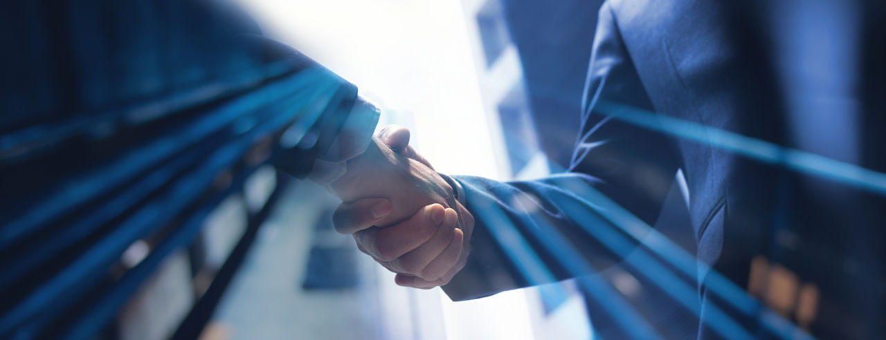 two people shaking hands with office buildings in the background