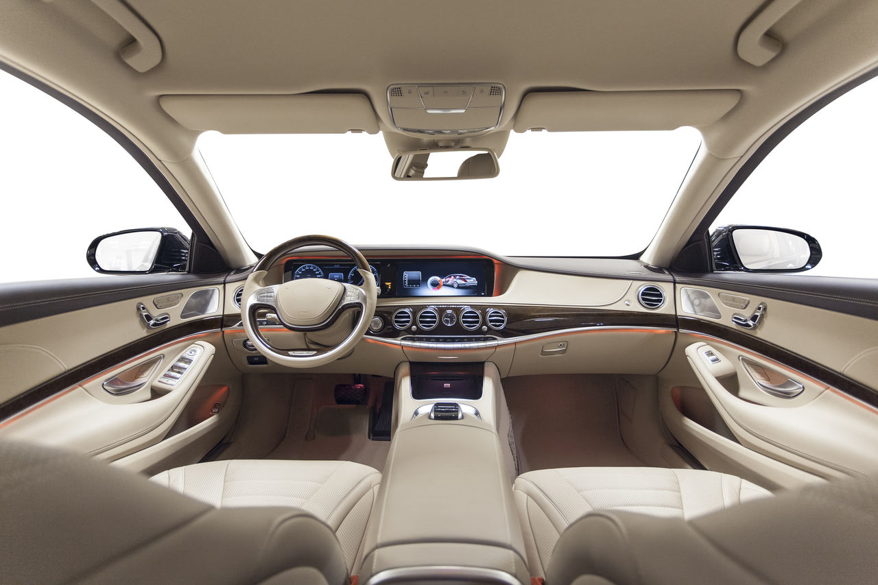 Car interior luxury. Beige comfortable seats, steering wheel, dashboard, climate control, speedometer, display, wood decoration & orange ambient light