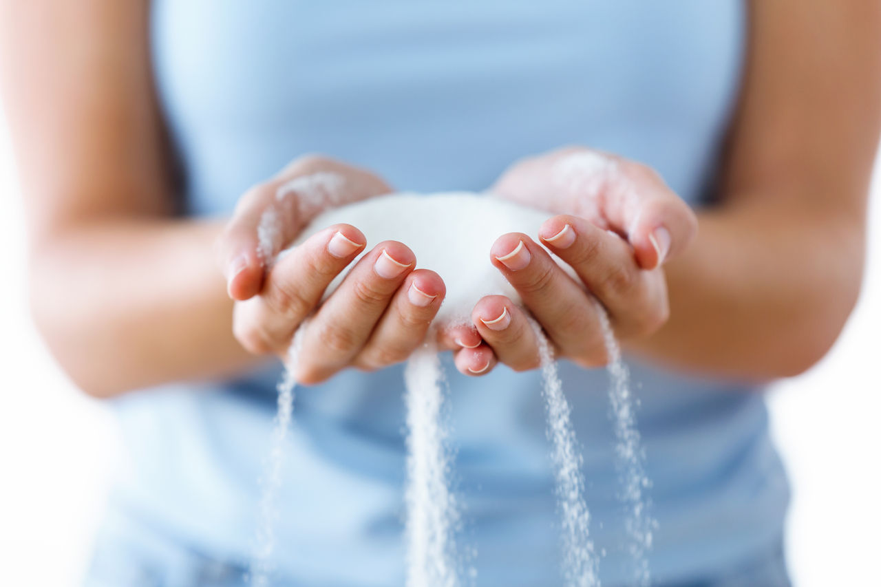 Close-up of white sugar in the woman hands. Heap of white sugar.; Shutterstock ID 1217732431; purchase_order: POL_Website_Recycled CaCO_Omyaloop FC; job: ; client: ; other: 