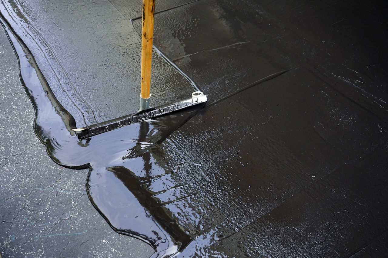 Person sealing asphalt driveway