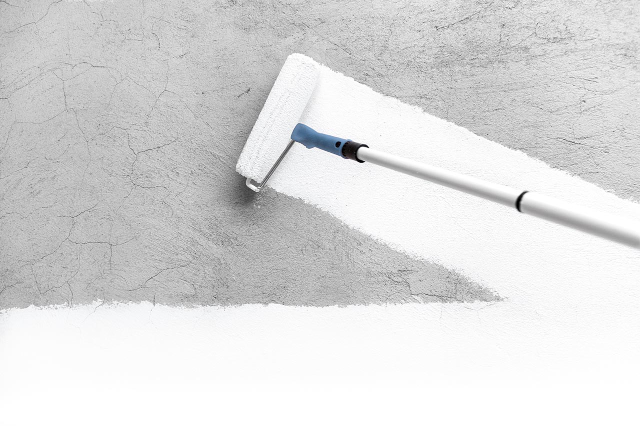 Paintbrush painting a wall white